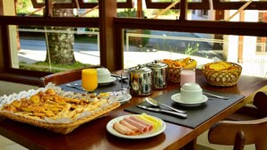 A breakfast table with croissants, ham, and eggs, along with coffee and juice.