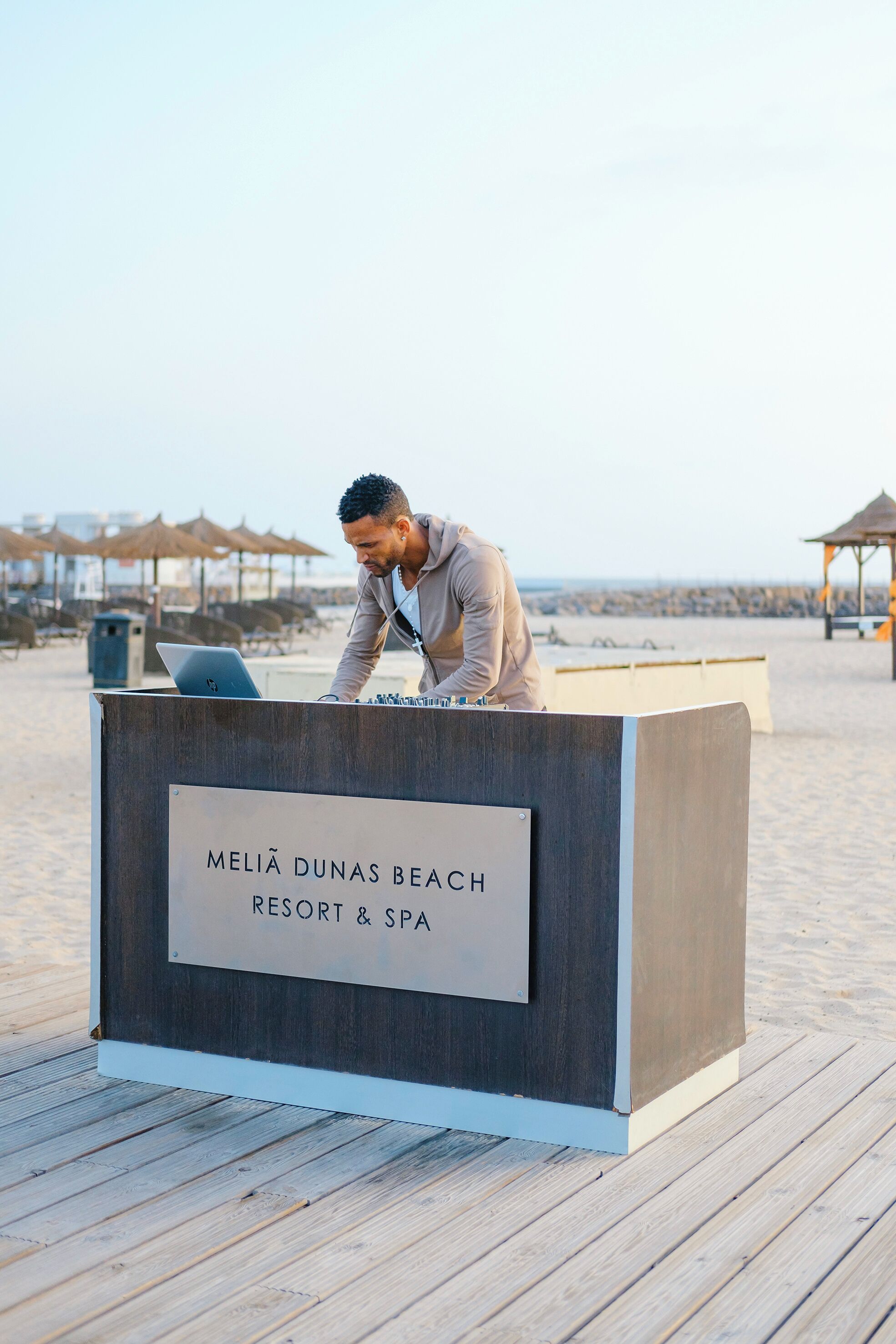A wooden reception desk with a sign reading "Meliá Dunas Beach Resort & Spa" on a wooden deck.
