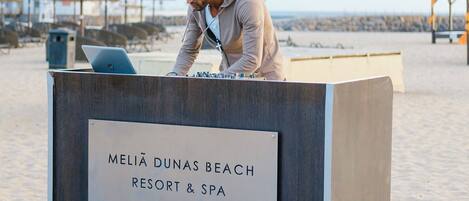 A wooden reception desk with a sign reading "Meliá Dunas Beach Resort & Spa" on a wooden deck.