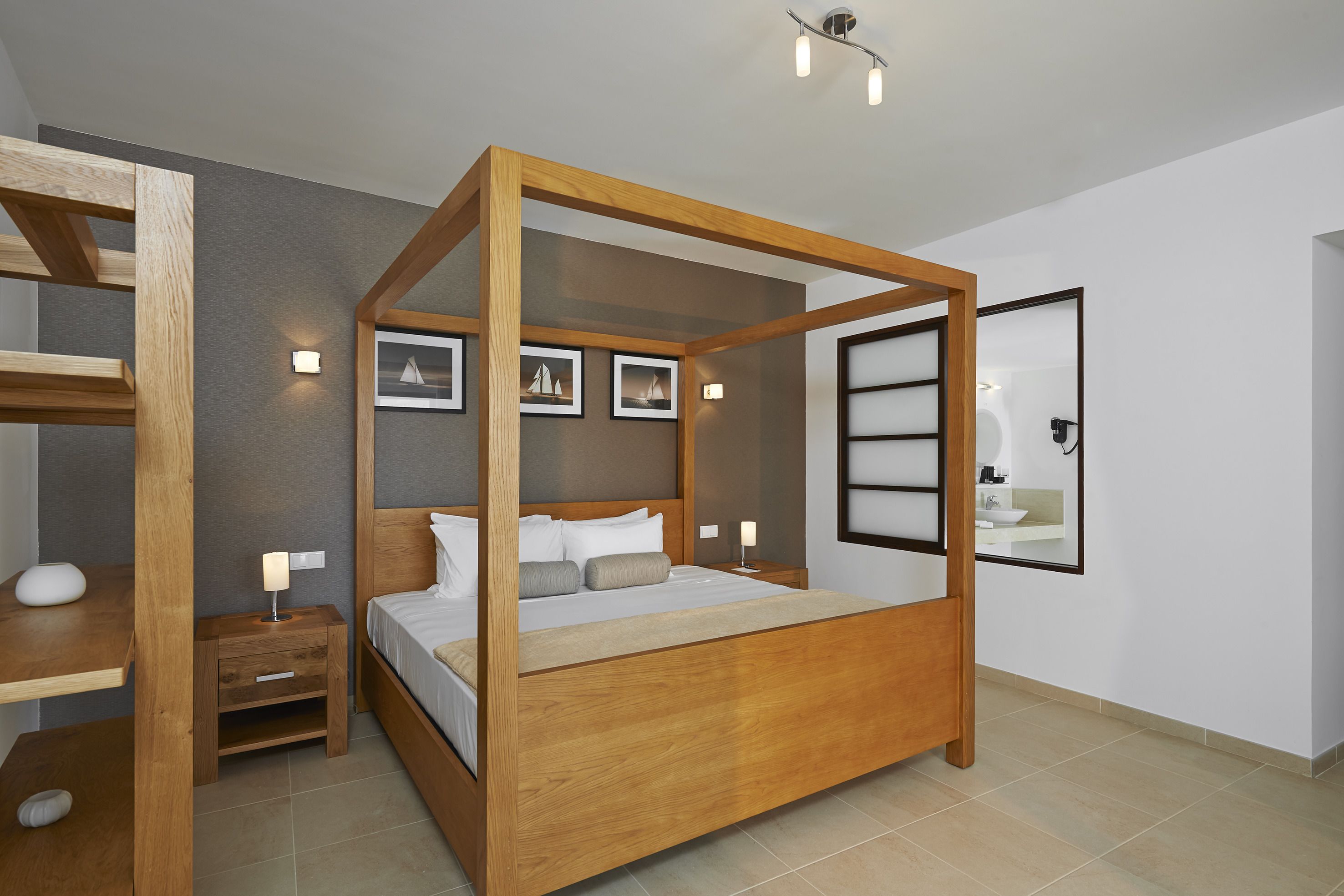 A modern bedroom with a wooden four-poster bed, bedside tables, and a large mirror.