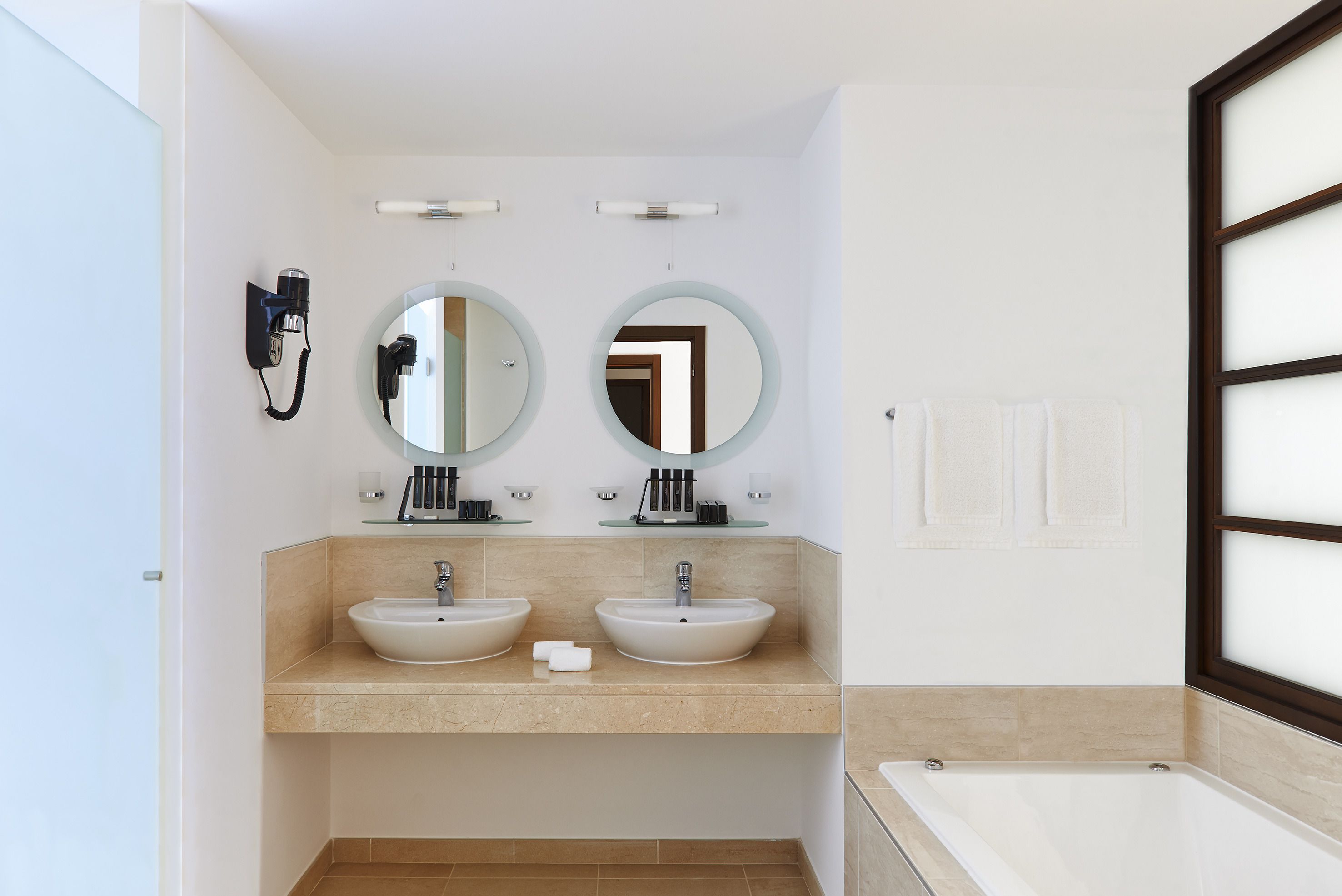 Un baño moderno con dos lavamanos, un espejo grande y una bañera.
