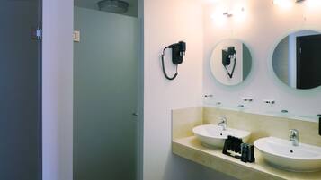 Un baño moderno con dos lavabos, un secador de pelo y un espejo.