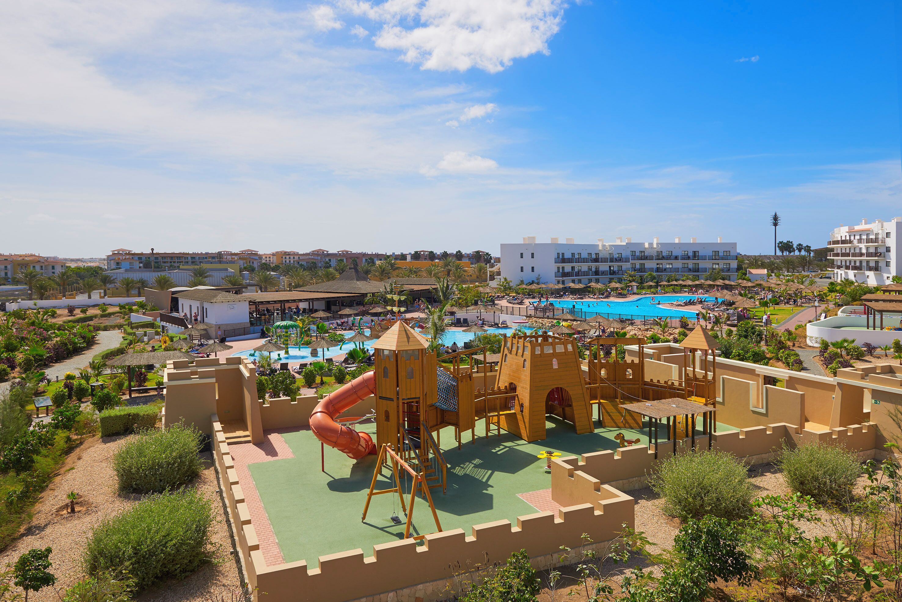 Un parque infantil con temática de castillo, piscina y edificios circundantes.