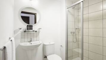 A modern bathroom with a white sink, toilet, and a glass-enclosed shower.