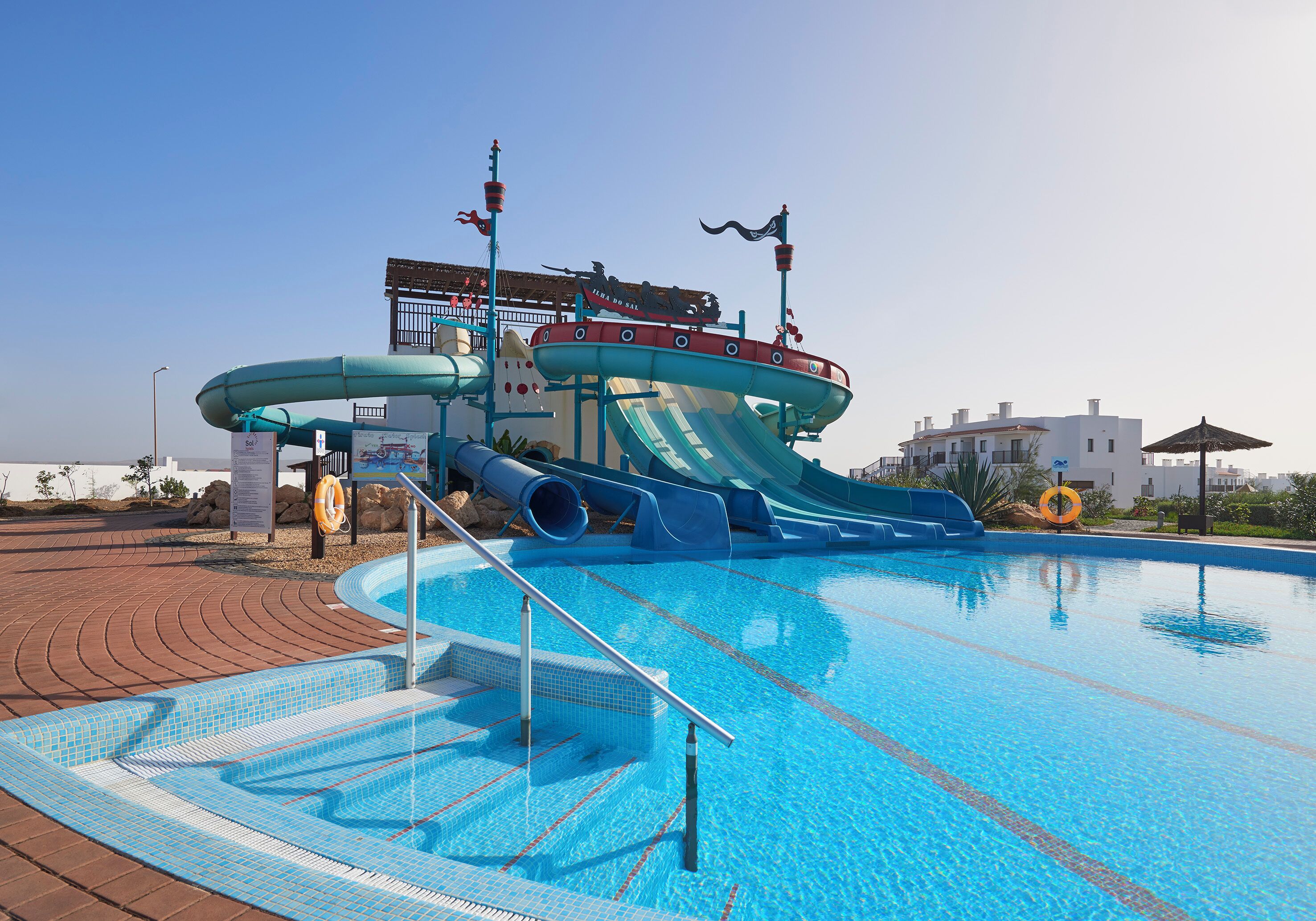Ein Schwimmbecken mit Wasserrutsche und Rettungsschwimmerstand.