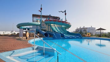 Ein Schwimmbecken mit Wasserrutsche und Rettungsschwimmerstand.
