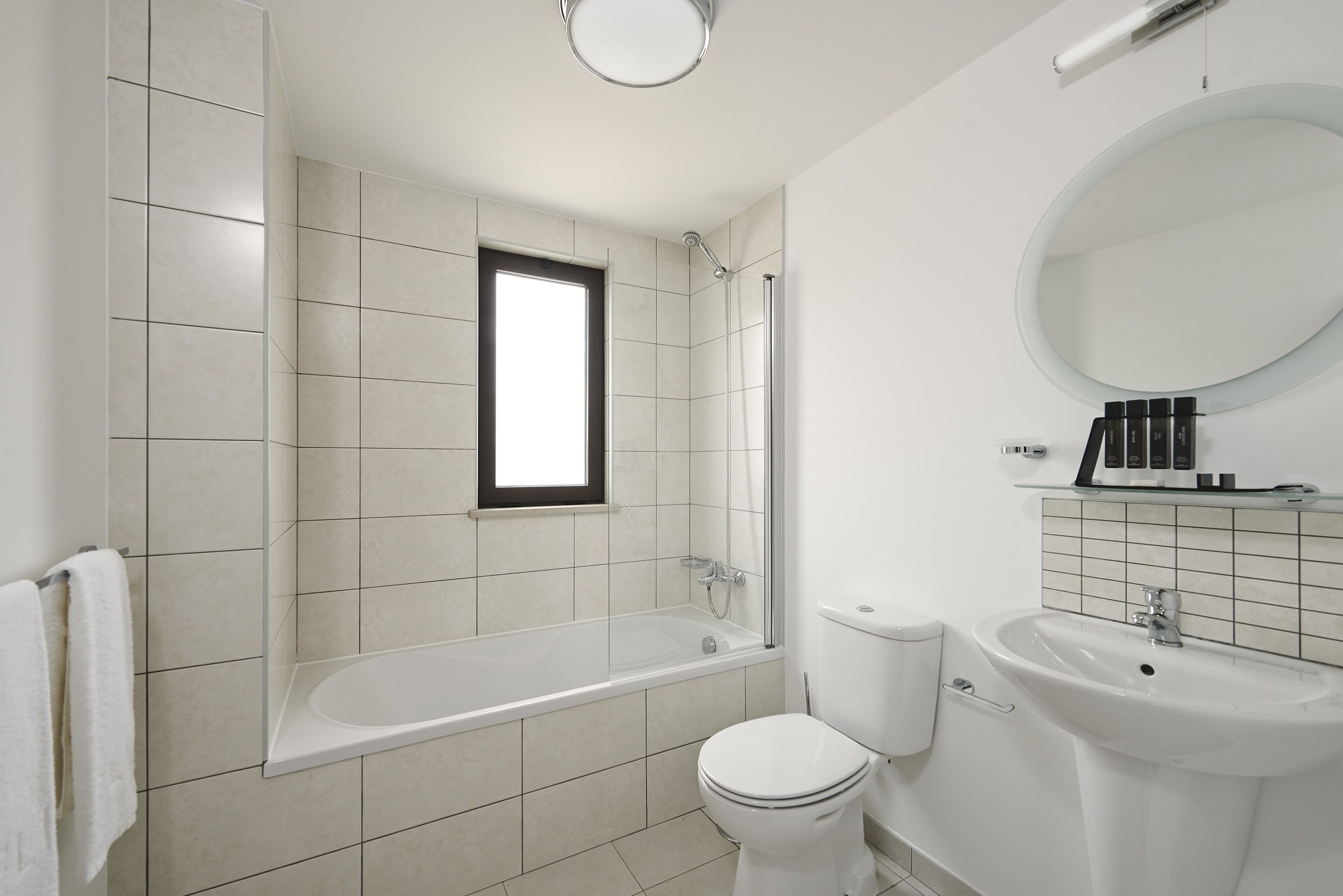 A modern bathroom with a bathtub, toilet, and sink.