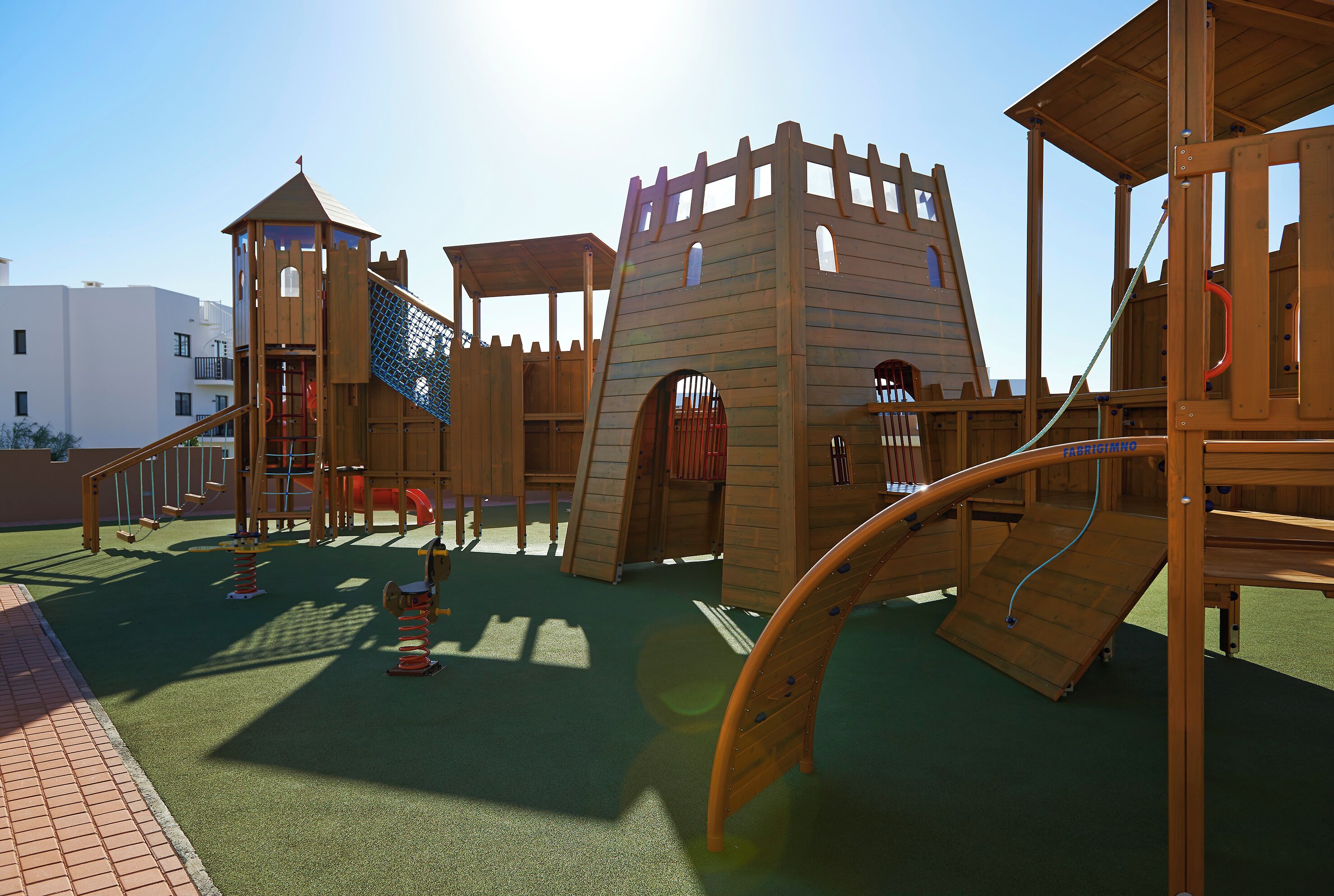 Un parque infantil con una estructura tipo castillo, toboganes y zonas de escalada.