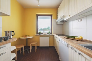 A compact kitchen with a wooden countertop, a small dining table, and a window with a view. - P&O Apartments Namyslowska (Warsaw)