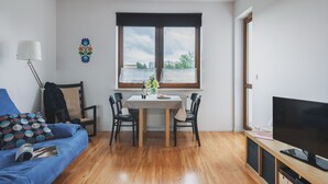 Un soggiorno moderno con tavolo da pranzo, sedie, divano, televisore e un'ampia finestra vista.