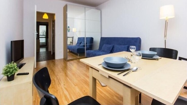 A modern dining area with a wooden table, blue chairs, and a blue sofa in the background.