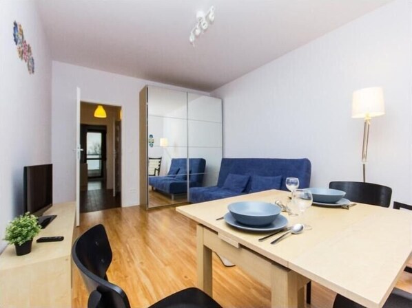 Un comedor moderno con una mesa de madera, sillas azules y un sofá azul al fondo.