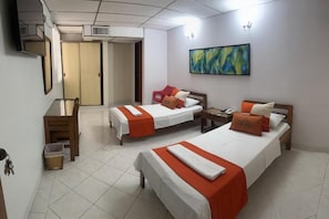 Habitación de hotel con dos camas, un escritorio, una silla y un cuadro en la pared.