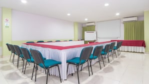 Un salón de conferencias con una larga mesa, sillas, una pizarra y un equipo de aire acondicionado.