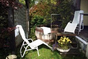 A garden with a wooden barrel, a white chair, a small table, and a flower pot. - Hotel Post (Grosskirchheim)