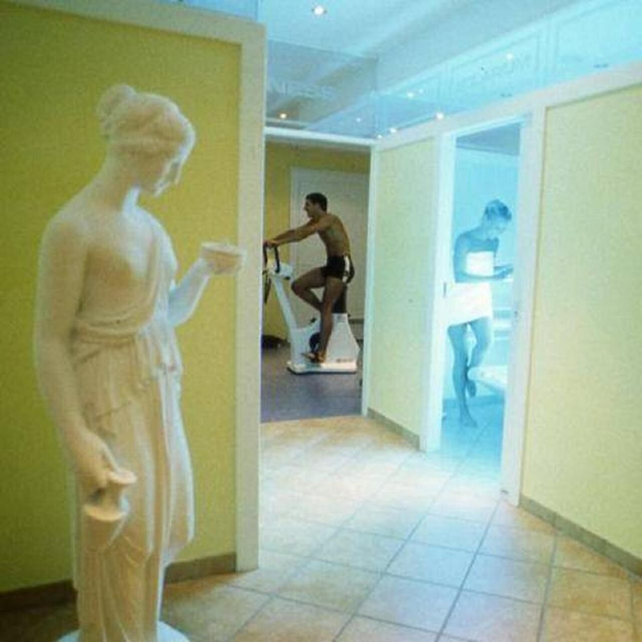 Una estatua en un pasillo con una persona ejercitándose en un aparato.