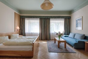 A hotel room with a bed, a sofa, a coffee table, and a lamp. - Hotel Post (Grosskirchheim)