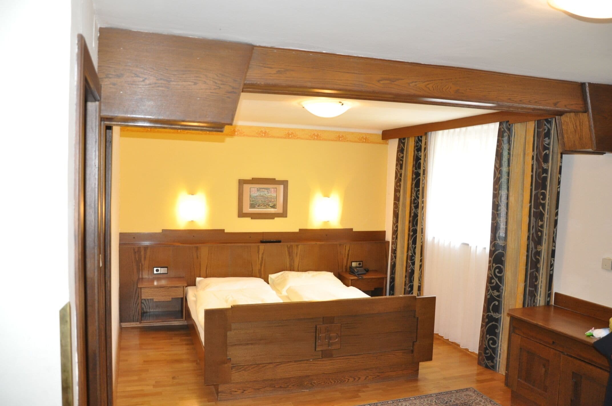 A bedroom with a wooden bed, bedside tables, a nightstand, and a dresser.
