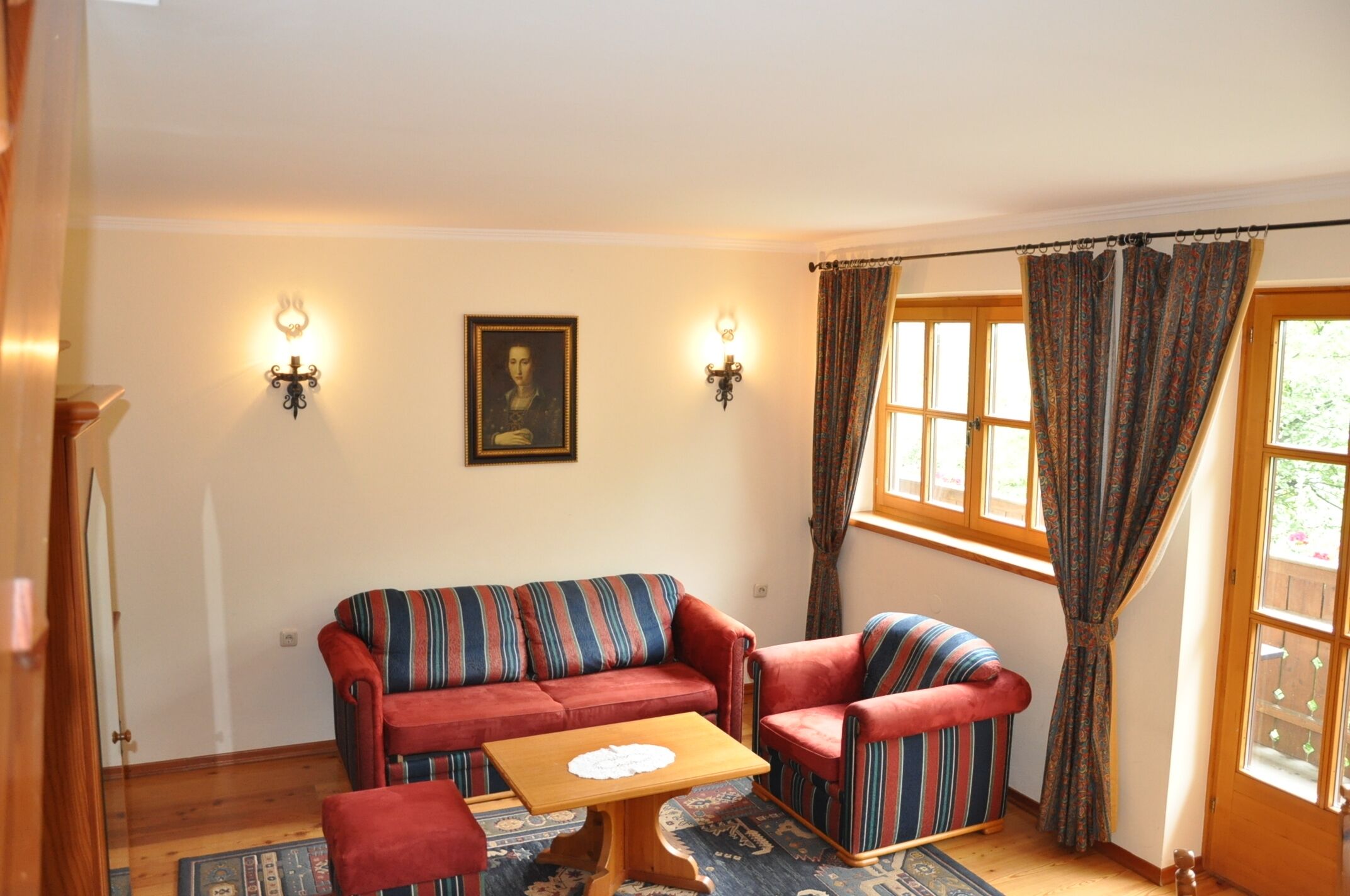 A living room with a striped sofa, a wooden coffee table, and two wall-mounted lamps.