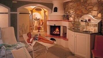 A room with a fireplace, a lounge chair, and a person relaxing.