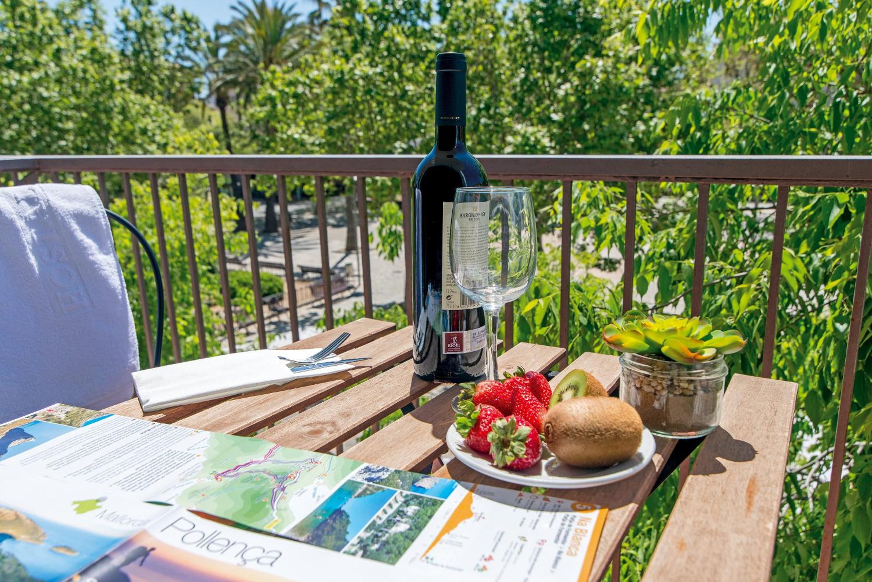 A wooden table with a bottle of wine, a glass, a plate of fruit, and a map.