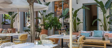 Ein Straßencafé mit Korbmöbeln, Pflanzgefäßen und Blick auf die Straße.