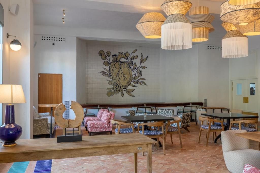 A hotel lobby with a large wall mural, multiple dining tables, and chairs.