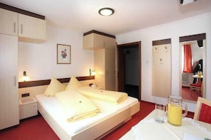 A hotel room with a bed, bedside tables, a mirror, a small table with a glass, and a pitcher of water.