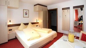 Hotellihuone, jossa on sänky, yöpöydät, peili ja pöytä, jonka päällä on kannullinen mehua.