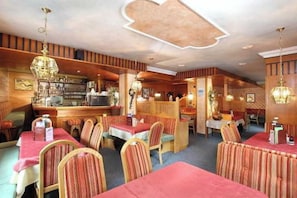 A restaurant with booths and tables, wooden paneling, and hanging pendant lights.