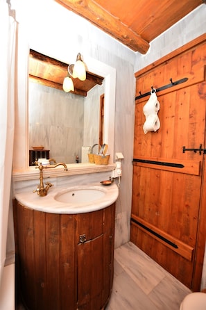 A bathroom with a wooden vanity, a large mirror, and a hanging towel rack. - Viglatoras Traditionals Apartments (Malevizi)