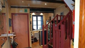 A hotel corridor with a wooden staircase, a door leading to a room, and a radiator in the background. - Albergue O Fogar de Teodomiro (Santiago de Compostela)