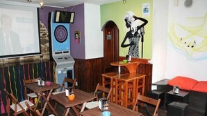 A restaurant with wooden tables and chairs, a dartboard, and a mural on the wall. - Albergue O Fogar de Teodomiro (Santiago de Compostela)