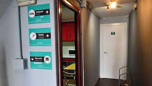 A hallway with directional signs for 'Habitación' (Room 001), 'Cocina' (Kitchen), and 'Sala común' (Lobby room). - Albergue O Fogar de Teodomiro (Santiago de Compostela)