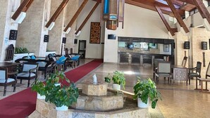 Un vestíbul ampli amb un sostre de fusta alçat, una font central i una zona de cuina al fons.