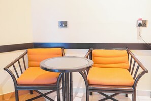Un coin salon avec deux fauteuils et une petite table ronde, une prise de courant et un interrupteur.