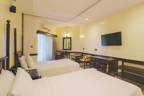 A hotel room with two beds, a desk, a chair, a television, and a window with curtains.