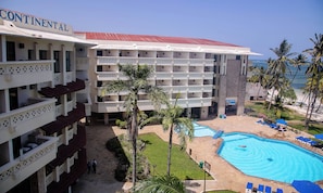 Un hôtel à plusieurs étages, doté d’une piscine et bordé de palmiers.