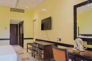 Une chambre d’hôtel comprenant un lit, un bureau avec des tiroirs, une chaise, un téléviseur fixé au mur et un miroir.