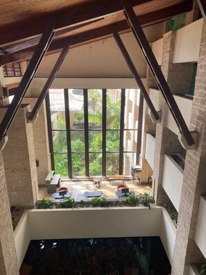 Un vaste atrium doté de hauts plafonds et de grandes fenêtres offrant une vue sur la verdure environnante.