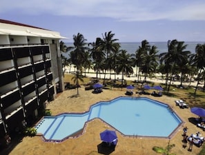 Un hôtel doté d’une piscine, d’une plage et de palmiers.