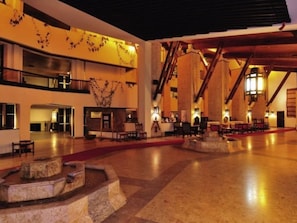 Un hall d’entrée spacieux avec un plafond haut, des colonnes en pierre et une fontaine centrale.