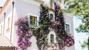 A pink villa with a balcony, surrounded by potted plants and a clear sky. - Capo Santa Fortunata (Sorrento)