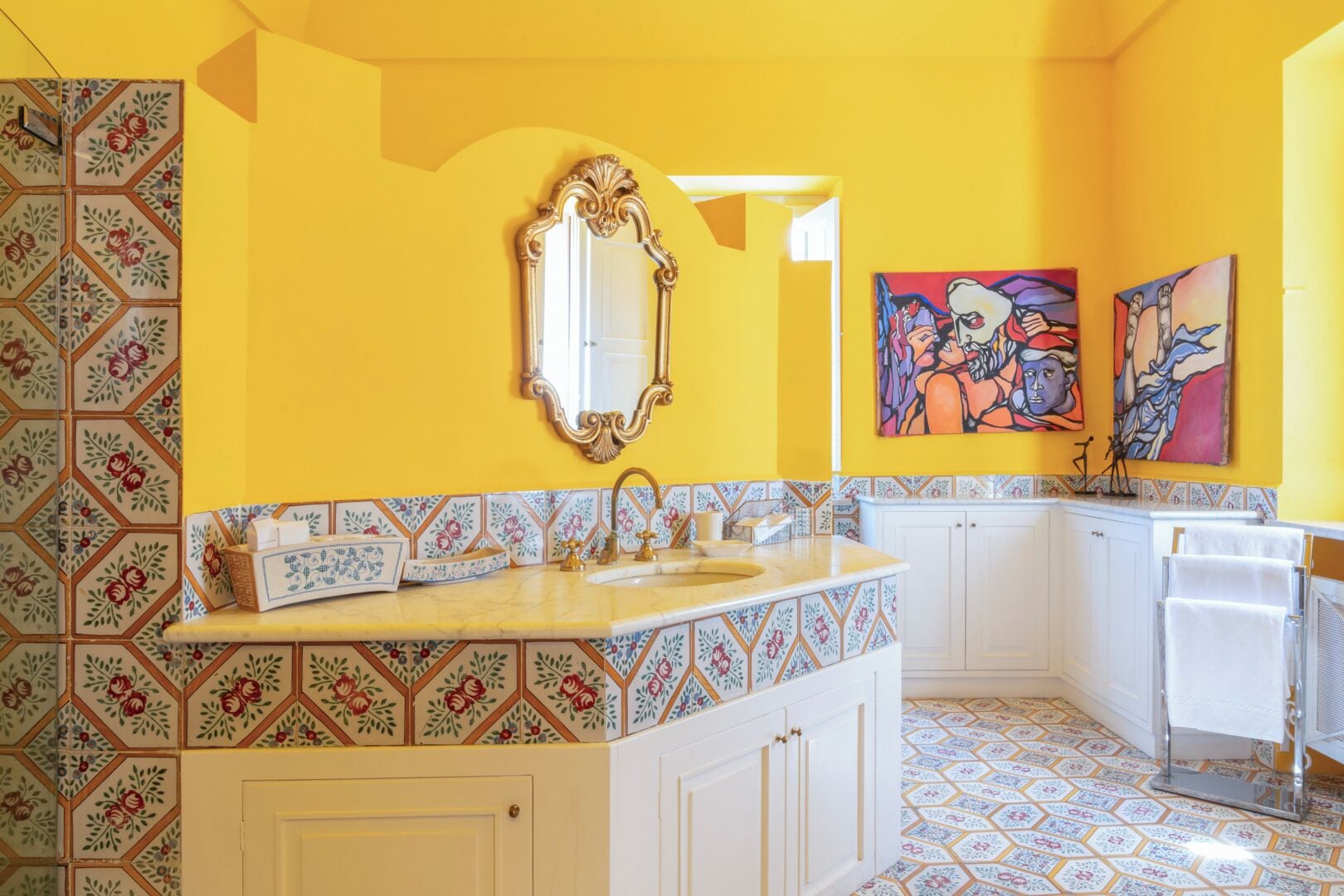 A bathroom with a yellow wall, a large mirror, a sink, and a shower area.