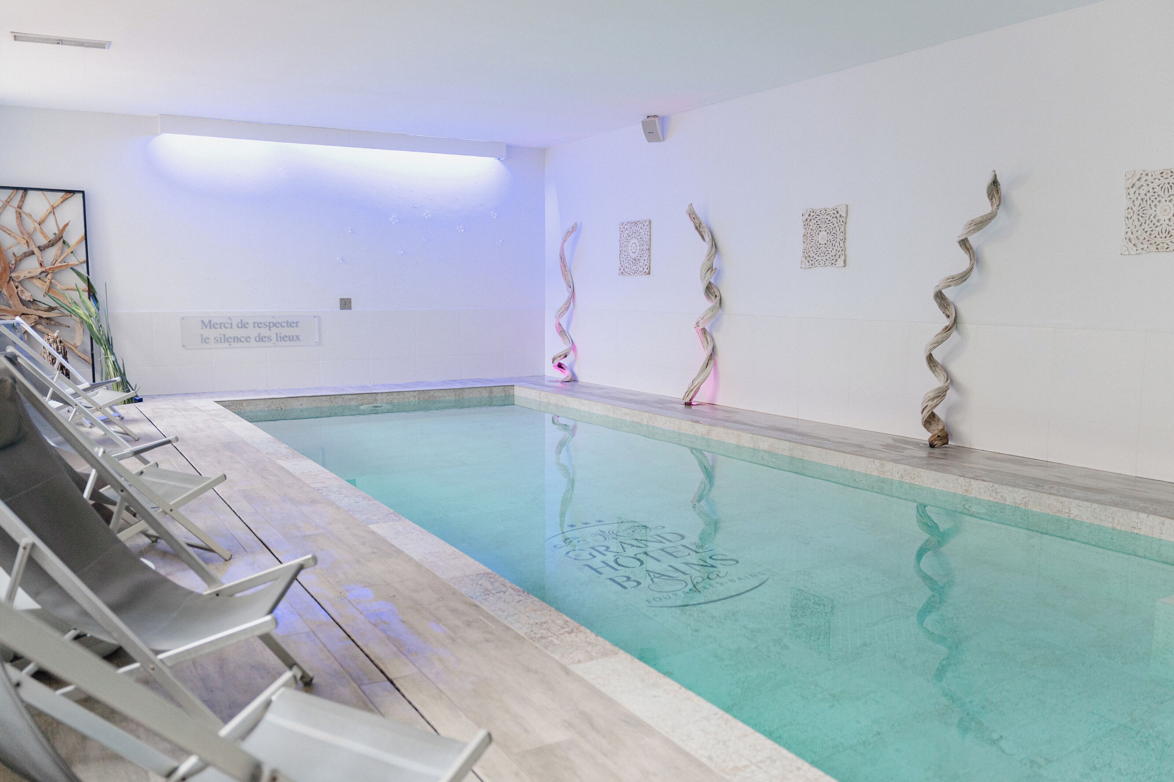 A swimming pool with lounge chairs and decorative wall art.