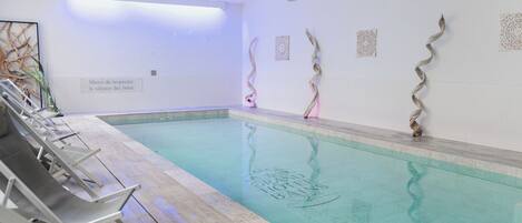 A swimming pool with lounge chairs and decorative wall art.