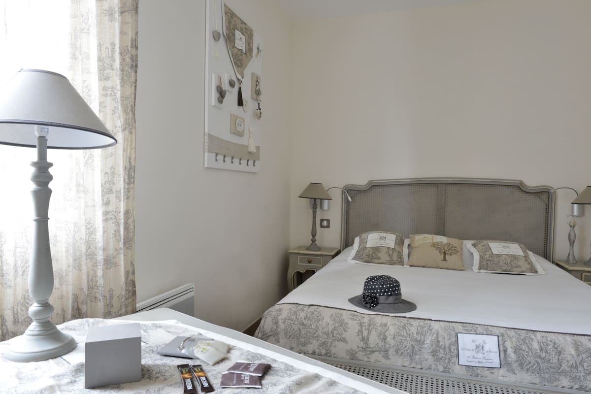 Une chambre à coucher bien rangée, avec un lit, des tables de chevet, une lampe et une commode.