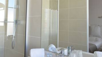 A modern bathroom with a white sink, a large mirror, and a glass-enclosed shower.