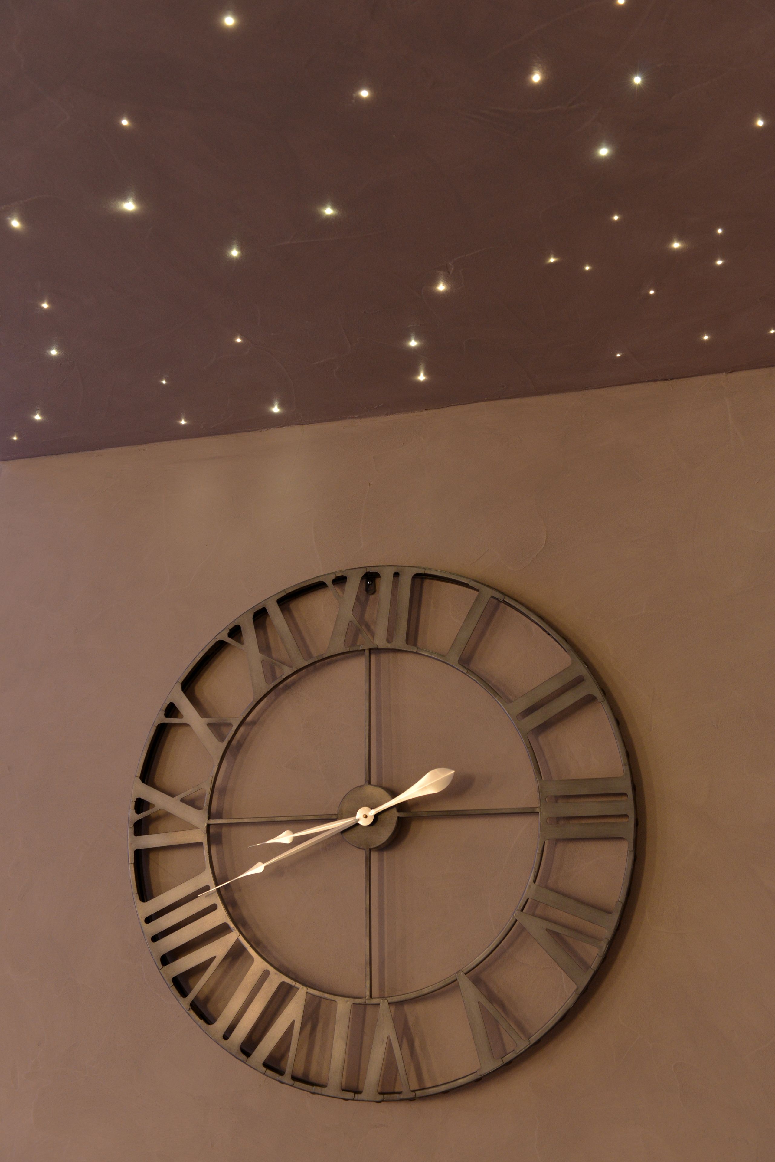 Une grande horloge murale de forme circulaire, avec des chiffres romains.