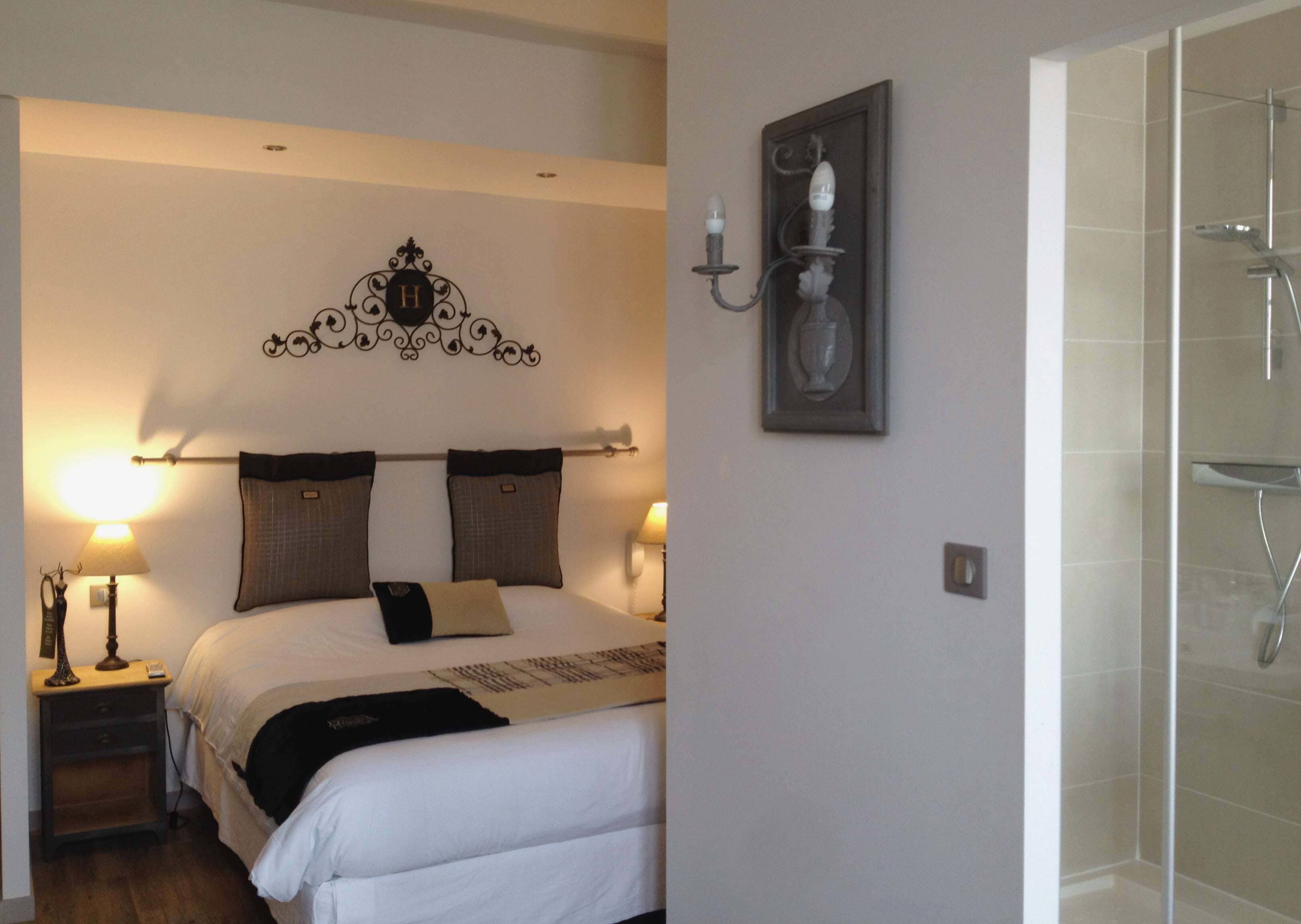 Una habitación de hotel con cama, lámparas de noche, un adorno en la pared y zona de ducha.